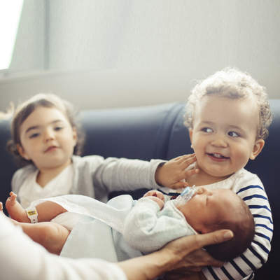 Brother and sister holding a newborn at the hospital