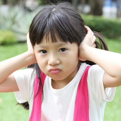 little girl covering her ears and expressing Negativity